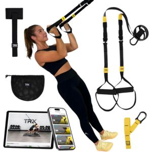 A woman using TRX straps surrounded by other TRX components and a mobile phone and tablet