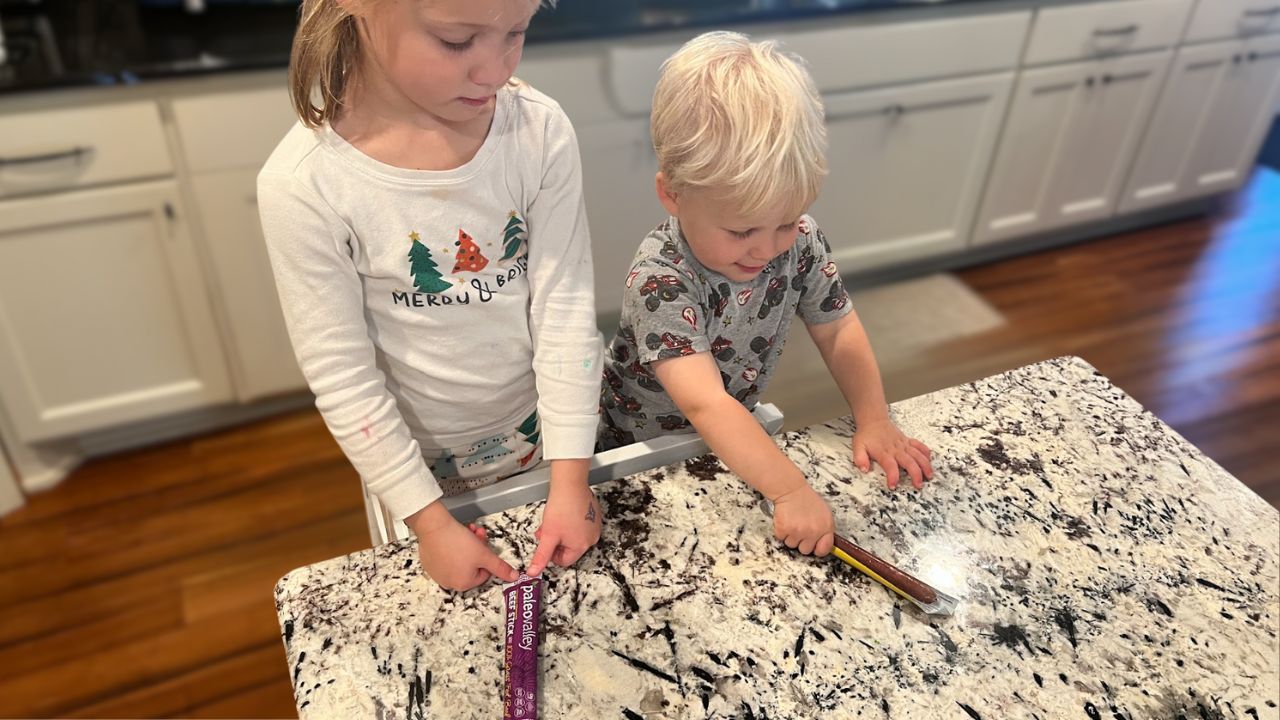 Little girl and boy with Paleovalley beef sticks in the kitchen.