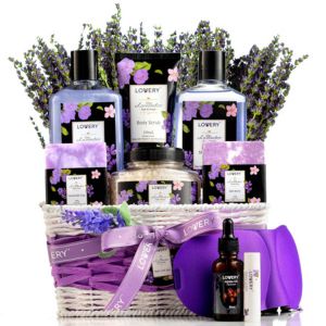 Lavender Gift Basket Lavender-themed bath and body gift basket filled with lotions, scrubs, shower gel, and accessories arranged in a white wicker basket with floral accents.