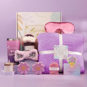Purple Gift Basket Purple-themed spa and relaxation gift box featuring an eye mask, blanket, candle, scrunchies, and floral bath accessories arranged on a pastel background.