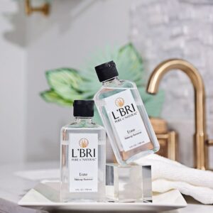 L'BRI non-toxic makeup remover on a bathroom counter with a gold faucet in the background.