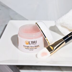 L'BRI Overnight Sleep Masque on a white dish next to a makeup brush.