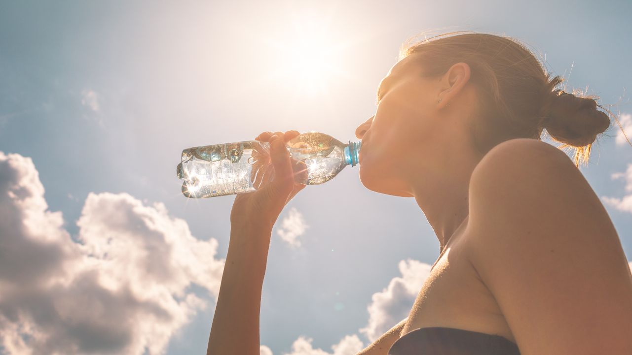 A woman recovering after a Pilates workout by hydrating with a bottle of water.