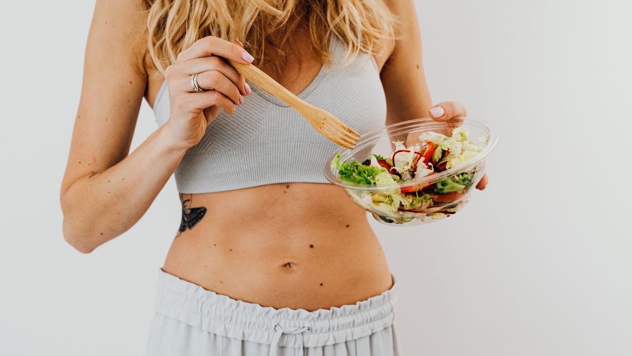 Woman Eating Salad A woman eating a bowl of salad.