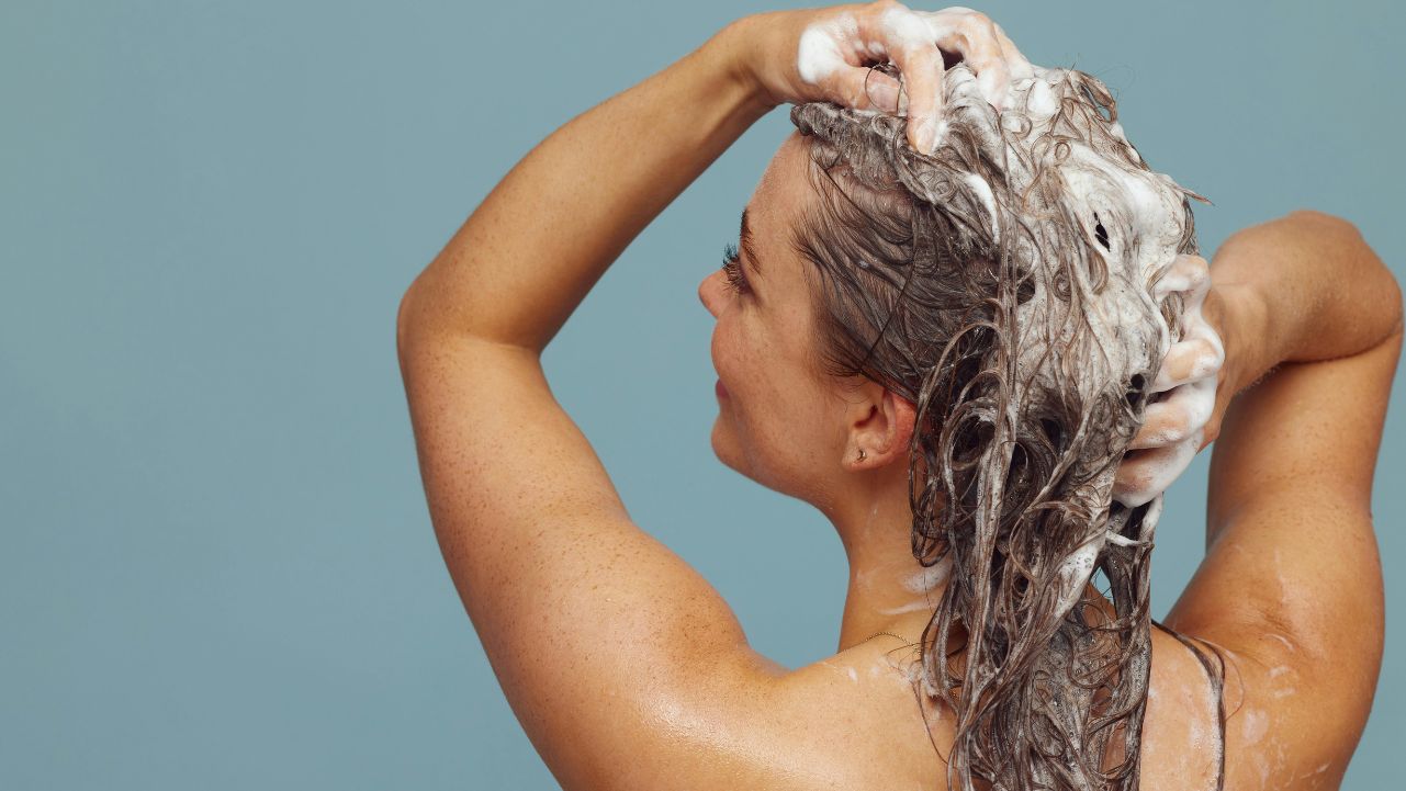 A woman shampooing her hair representing how to take care of your hair in summer