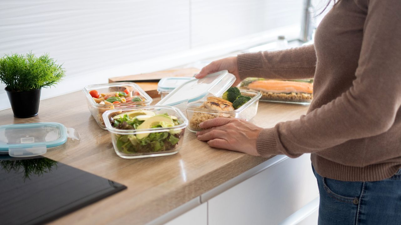 Woman putting food in containers for fridge reset